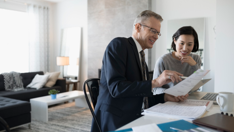 A woman reviewing financial documents with her advisor